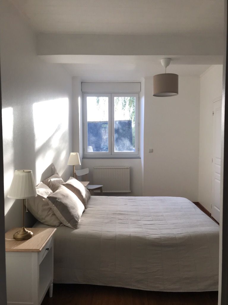 A bedroom with a bed, bedside lamps, a window, and a radiator.