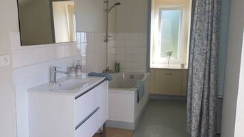 Et moderne badeværelse med badekar, håndvask og bruser.