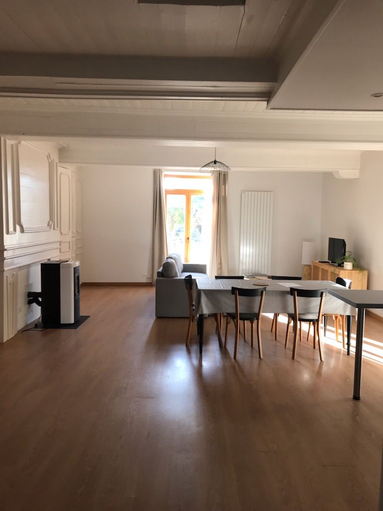 Een ruime woonkamer met een eettafel, stoelen en een bank.