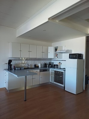 A modern kitchen with white cabinets, a stainless steel countertop, and a built-in oven.