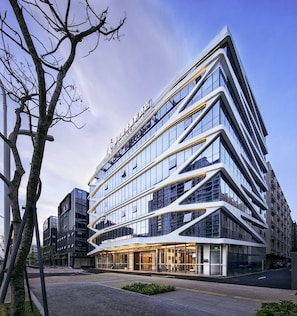 Een meerlaags hotel met een modern architectonisch ontwerp, met een opvallende ingang en een glazen gevel.
