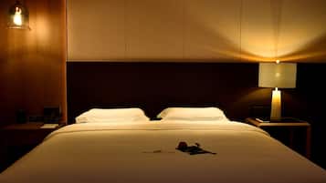 A hotel room with a bed, a nightstand, a lamp, and a hanging light fixture.