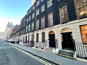 A row of black and white townhouses with a white facade, black iron railings, and a clear sky. - Stunning Studio Flat, Charring Cross Prime Location of London (London)