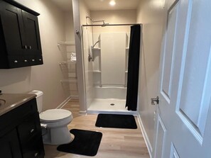 A compact bathroom with a toilet, a shower enclosure, and a cabinet. - Private 2BR Guest Suite, No Stairs, Garage (Woodstock)