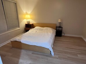A bedroom with a bed, two bedside tables, a lamp on each, and a window with blinds. - Private 2BR Guest Suite, No Stairs, Garage (Woodstock)