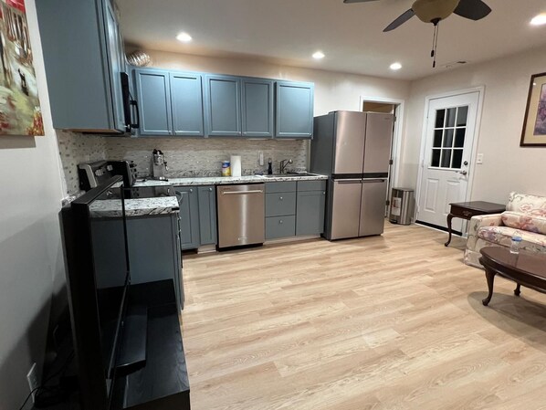 A compact kitchen with grey cabinets, a stainless steel refrigerator, and a dishwasher.