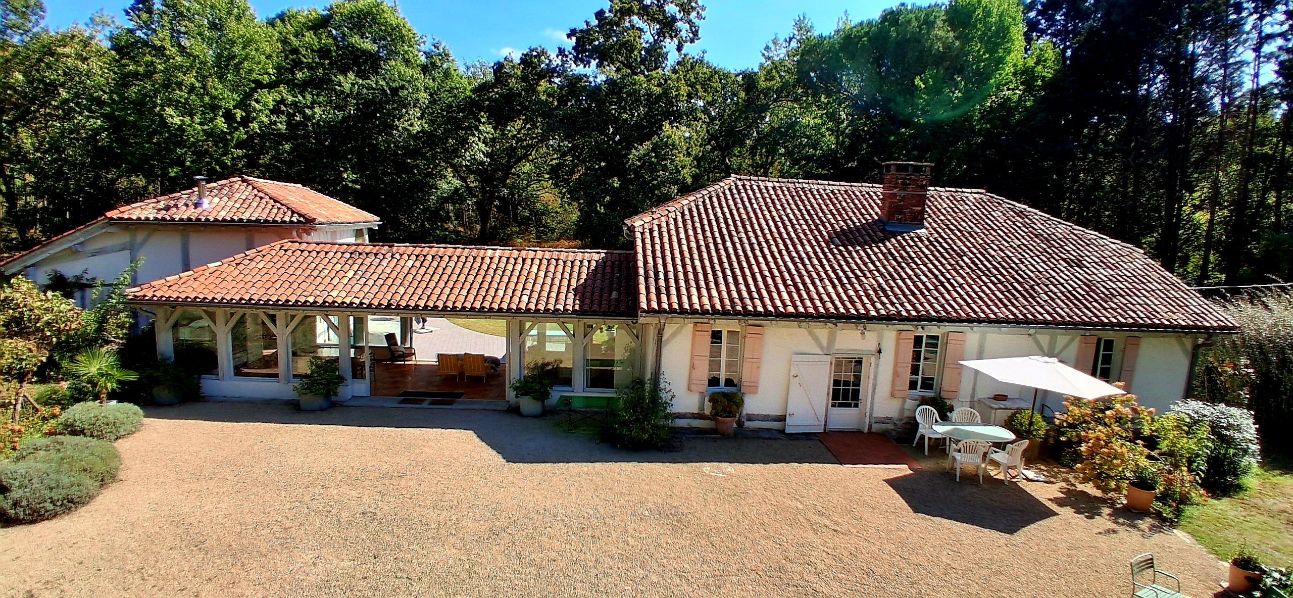 A two-story building with a tiled roof, a covered patio, and a gravel driveway.