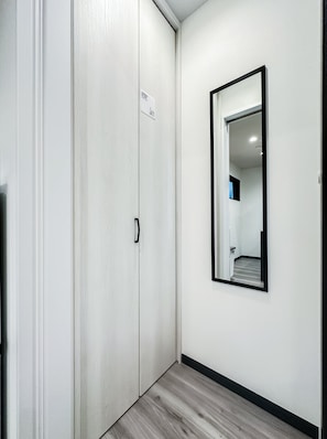 A hallway with a white door, a black-framed mirror, and a light-colored floor. - HANASTAY MUKAI HOTARU (Osaka)