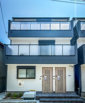 A two-story building with a flat roof, large windows, and a set of double doors. - HANASTAY MUKAI HOTARU (Osaka)