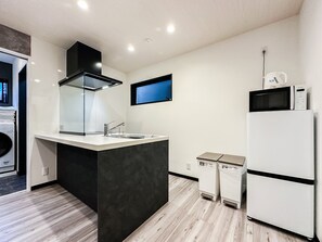A modern kitchen with a central island, a built-in oven, and a microwave on the counter. - HANASTAY MUKAI HOTARU (Osaka)