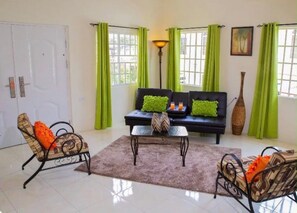 A living room with a sofa, two armchairs, a coffee table, and a lamp. - A welcoming light open concept two bedroom apartment. (San Juan)