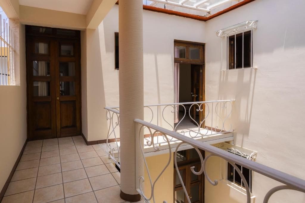 Un pasillo con piso de baldosas, una puerta de madera y un pilar blanco.