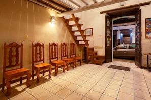 A room with a tiled floor, wooden chairs, a wooden staircase, and a car parked outside. - Hotel Niut-Ja (Oaxaca)