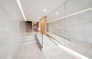 A modern interior with a marble floor, glass walls, and a staircase leading to another level. - Apartment next to the beach - 4P (Arcachon)