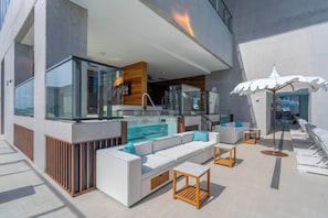 A modern outdoor lounge area with a pool, seating, and a glass-enclosed bar. - E11EVEN Miami Elevated Luxury Living (Miami)