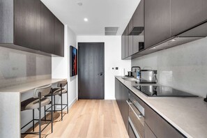 A modern kitchen with dark cabinets, a wooden floor, and a bar area with stools. - E11EVEN Miami Double Vacation (Miami)