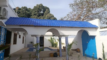 Un bâtiment doté d’un toit recouvert de tuiles bleues, de murs blancs et d’un patio abrité avec des colonnes.