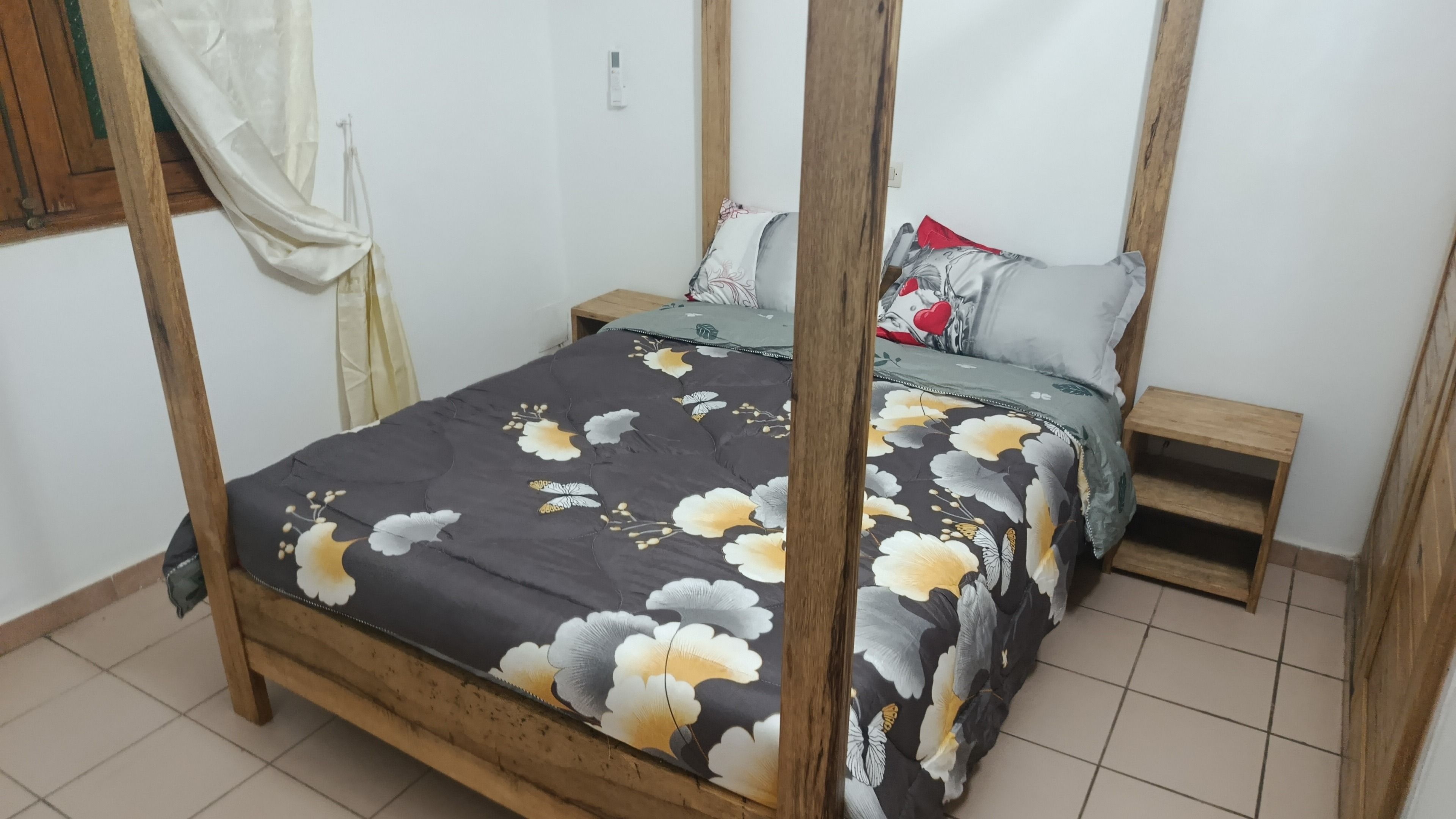 Un lit avec une couvre-lit à motifs floraux, une tête de lit en bois et une table de chevet avec une lampe.