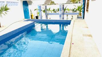 Una piscina amb vora de rajola blava, envoltada per un edifici blanc amb detalls blaus i columnes.