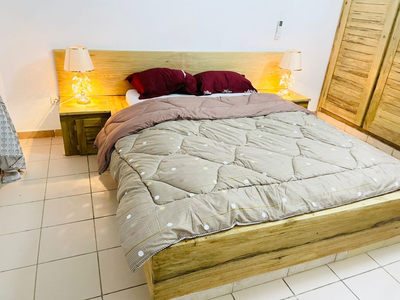 A bed with a wooden headboard, two bedside tables with lamps, and a wardrobe.