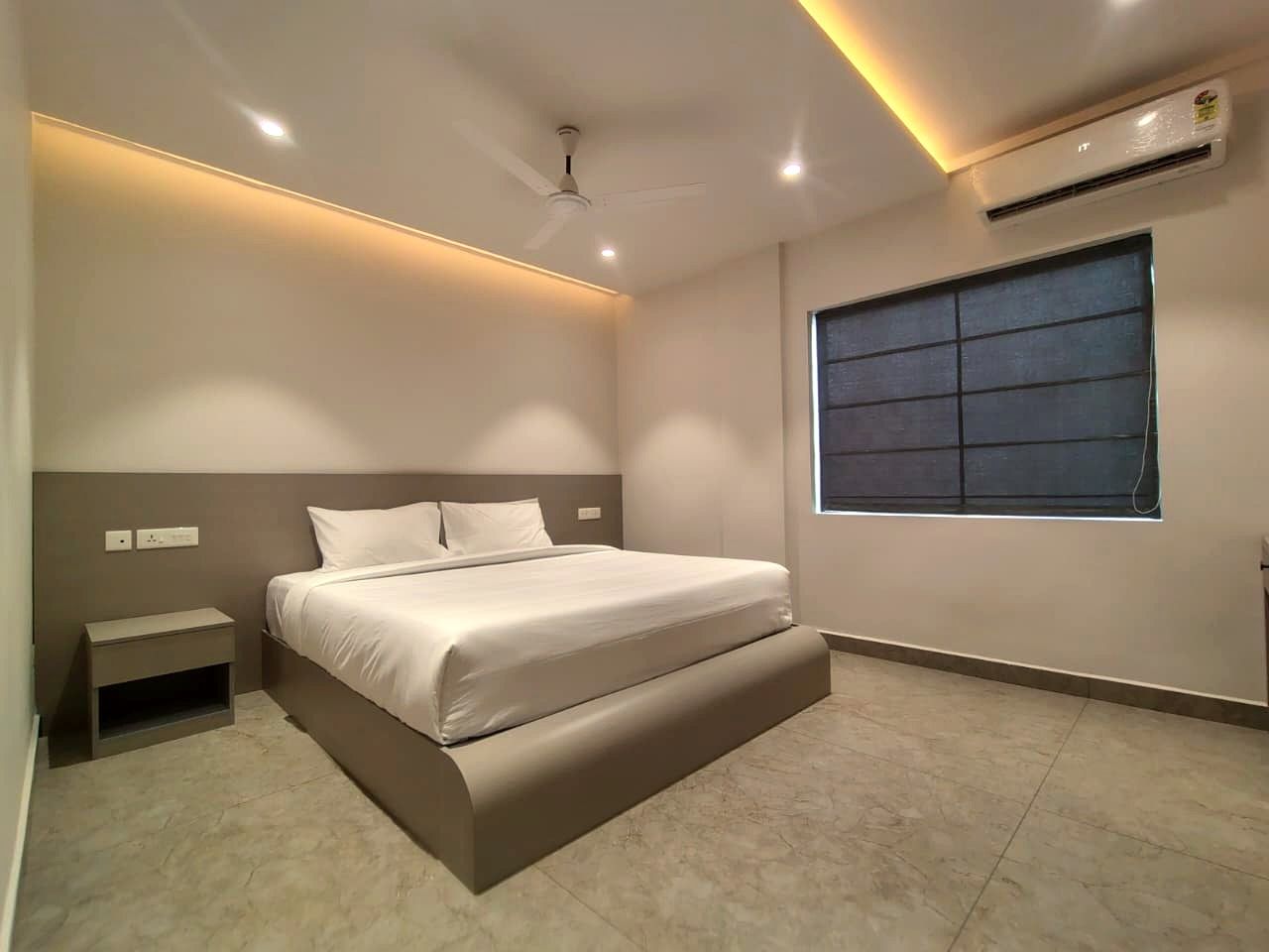 Quarto com cama, mesa de cabeceira e janela.