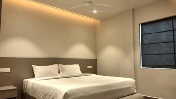 Quarto moderno com cama, mesa de cabeceira e ventilador de teto.