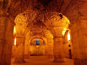 An interior with stone arches and columns, a central arched window, and a stone floor. - Modern and practical studio apt in the heart of Split (Split)