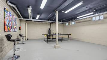 Une pièce avec une table de ping-pong, des chaises et des œuvres d’art accrochées au mur.