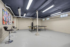 Een kamer met een tafeltennistafel, stoelen en kunst aan de muur.