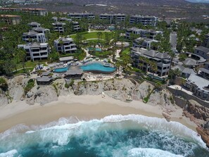Ein Resort mit mehreren Schwimmbecken, direkt am Strand und einer felsigen Küstenlinie.