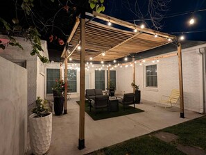 A covered patio area with seating, string lights, and potted plants. - Solost SOMA Little Rock (Little Rock)