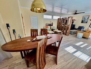 A spacious dining area with a wooden table and chairs, a ceiling fan, and a view of the living room. - Solost SOMA Little Rock (Little Rock)