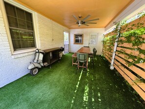 A patio with artificial grass, a table, chairs, a scooter, and a ceiling fan. - Solost SOMA Little Rock (Little Rock)