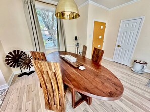 A dining area with a round wooden table, chairs, a windmill decoration, and a pendant light. - Solost SOMA Little Rock (Little Rock)