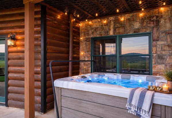 Un jacuzzi con vistas al exterior, rodeado de troncos de madera y paredes de piedra.