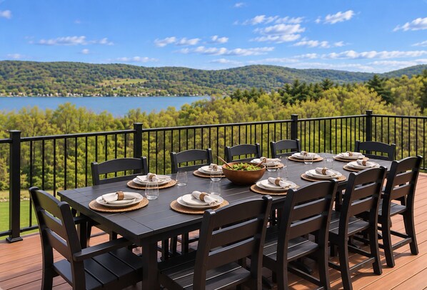 A deck with a table set for six, overlooking a lake and hills.