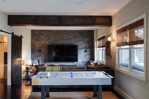 A living room with a fireplace, a sofa, a coffee table, and a pool table.