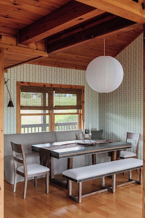 Un comedor de madera con un banco, una mesa y sillas.