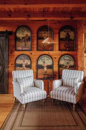 Una habitación con dos sillones a rayas, un tapete tejido y una pared decorada con carteles de béisbol antiguos.