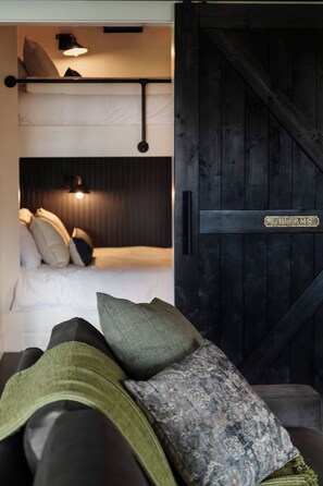 Una habitación con una cama, un sofá y una puerta de madera grande con una placa.