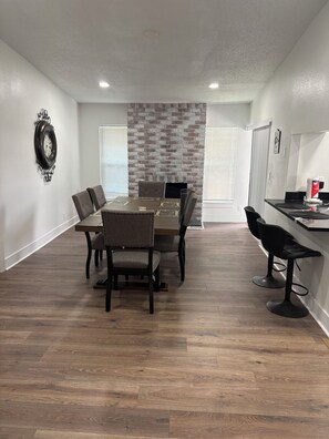 A dining area with a brick accent wall, a clock, and a bar area with stools. - Spacious 4-bedroom house in beautiful Kissimmee (Kissimmee)