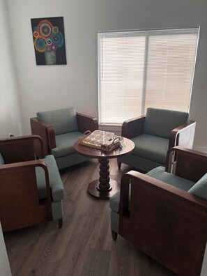 A room with two grey armchairs, a wooden coffee table, and a window with blinds. - Spacious 4-bedroom house in beautiful Kissimmee (Kissimmee)