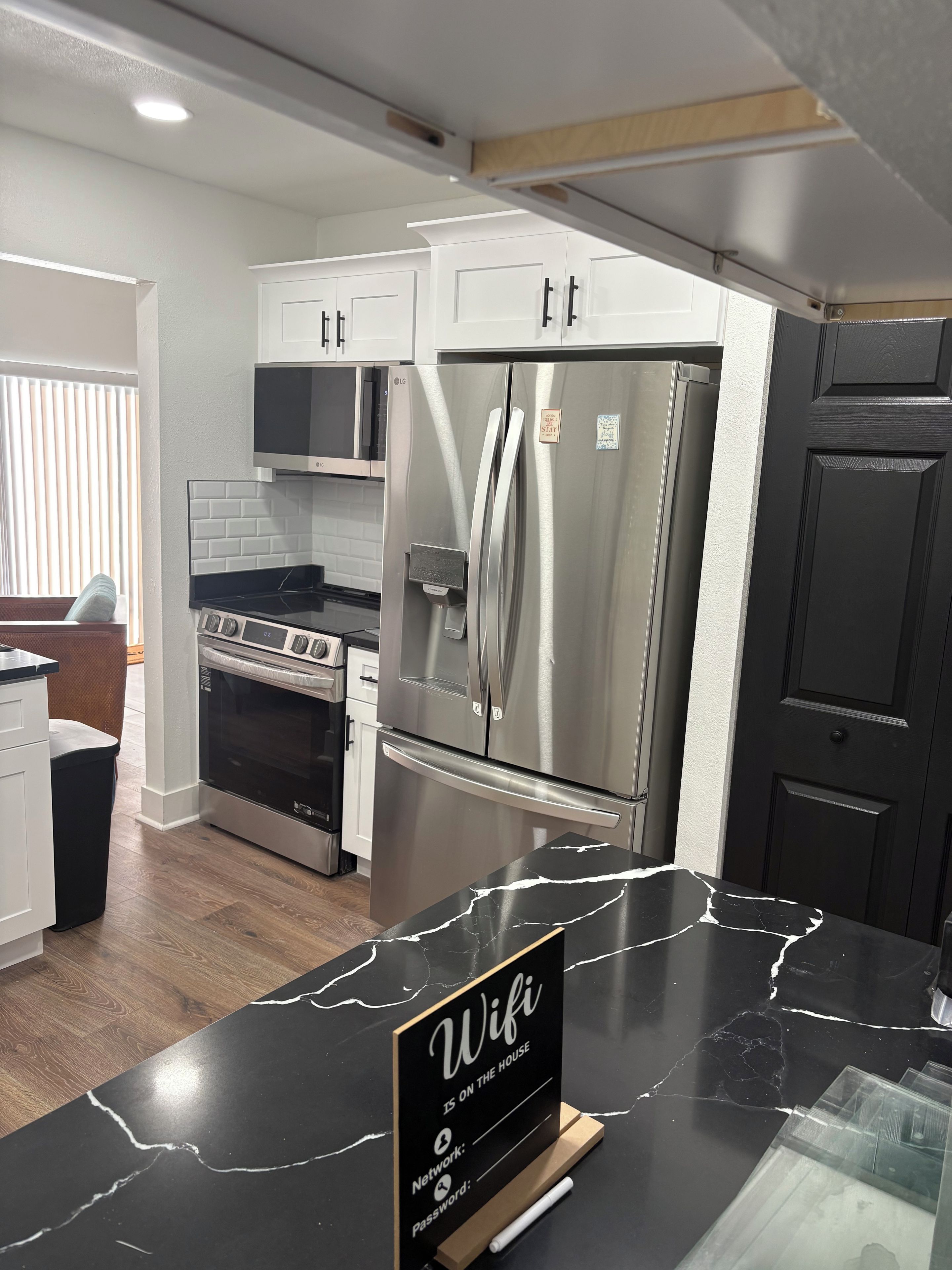 A modern kitchen with stainless steel appliances, a marble countertop, and a sign indicating WiFi availability.