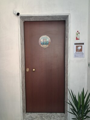 A brown door with a circular emblem and a sign indicating a video surveillance area. - Aster Rhegion Apartment Your Vacation Home Reggio Calabria,Beach, City Mountains (Reggio Calabria)