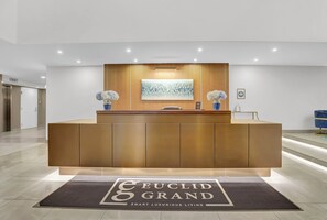 A reception desk with a modern design, a framed abstract painting above it, and a logo on the floor mat. - PremiumStays: 2 bd loft w/balcony : Playhouse sq : Theater : Arena : Parking (Cleveland)
