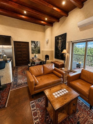 A spacious living area with leather sofas, a wooden coffee table, and a large window offering a view of the outdoors.