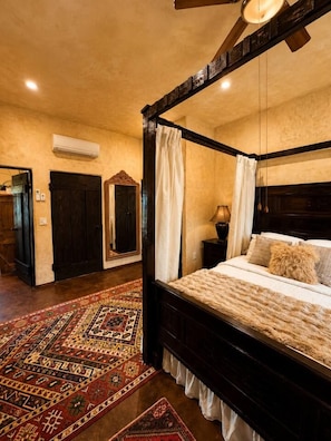A four-poster bed with a canopy, a patterned rug, and a ceiling fan.