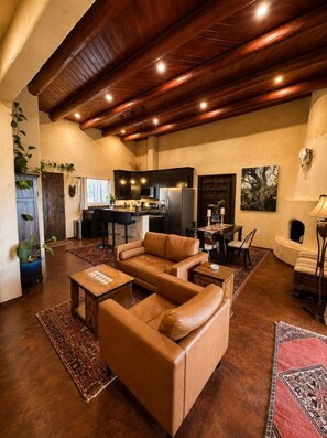 A spacious living area with a brown leather sofa, a wooden coffee table, and a kitchen in the background.
