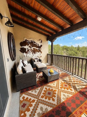 A covered outdoor seating area with a patterned rug, a sofa set, and a coffee table.