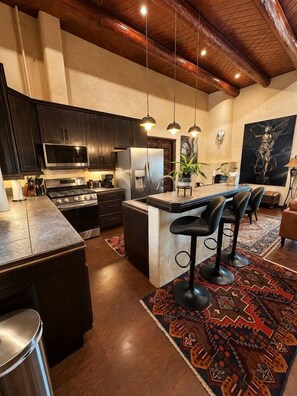 A modern kitchen with dark cabinetry, a central island with bar stools, and pendant lighting.